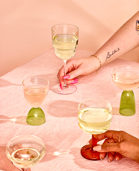 Two hands hold glasses of Fre alcohol-removed white wine