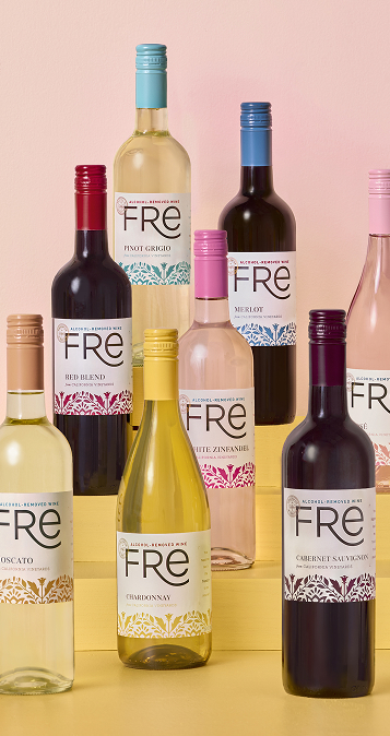 Group of FRE Alcohol-Removed wine bottles arranged in a tier, on a yellow surface with a pink background