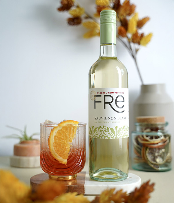 color image of a bottle of FRE Alcohol-Removed Sauvignon Blanc with an orange cocktail with an orange slice as a garnish