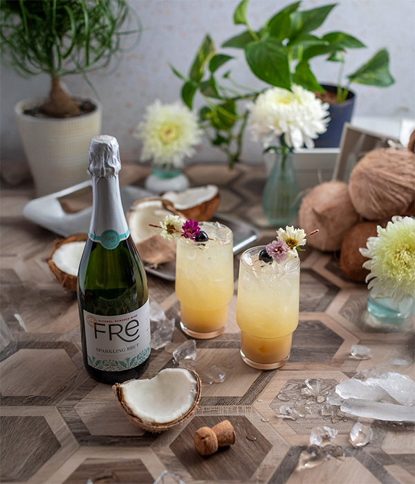 color image of a bottle of FRE Alcohol-Removed Sparkling Brut with two cocktails on a table with flowers