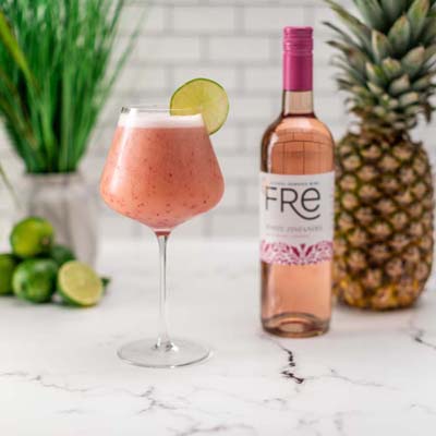color image of a bottle of FRE Alcohol-Removed White Zinfandel next to a pink slushie mocktail and a pineapple