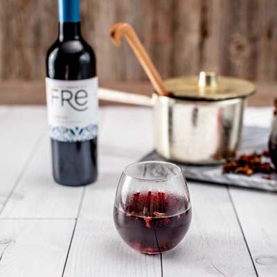 color image of a dark red mocktail with a bottle of FRE Alcohol-Removed Merlot in the background