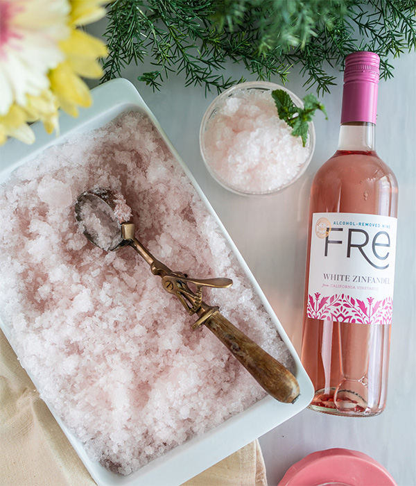 color photo of pale pink slushie ice next to a bottle of FRE Alcohol-Removed White Zinfandel