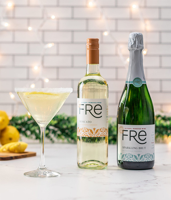 color image a bottle of FRE Alcohol-Removed Moscato and FRE Alcohol-Removed Sparkling Brut next to a mocktail on a white counter