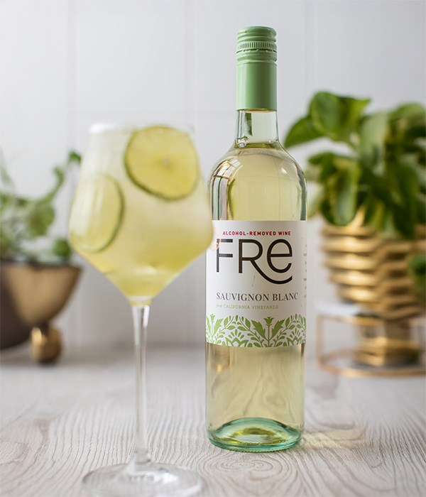 Color image of a bottle of FRE Alcohol-Removed Sauvignon Blanc with a wine glass of spritz and lime slices