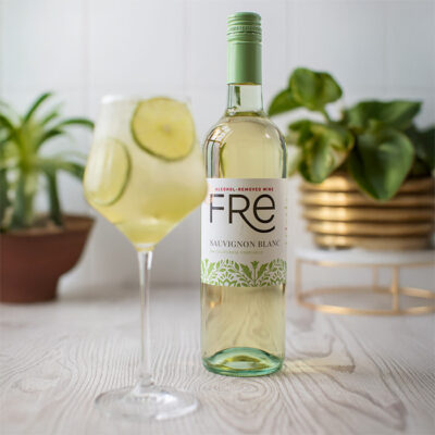 Color image of a bottle of FRE Alcohol-Removed Sauvignon Blanc with a wine glass of spritz and lime slices