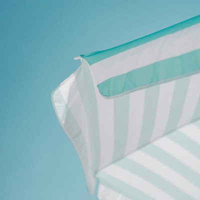 Abstracted photo of a blue and white striped table umbrella against a blue sky