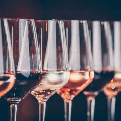 Close up of a row of red, white, and rosé glasses of wine